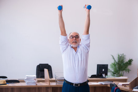 Old businessman employee doing sport exercises in the officeの写真素材