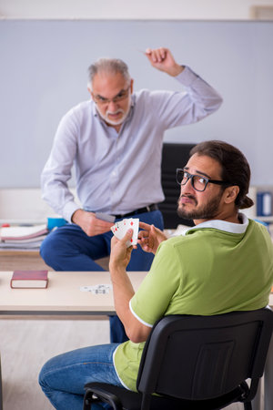 Old male teacher and young male student playing card in the clasの写真素材