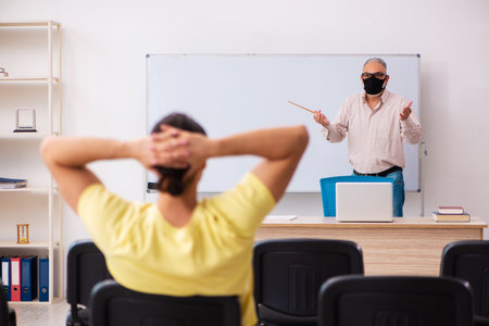 Young male student and experienced teacher in pandemic conceptの写真素材