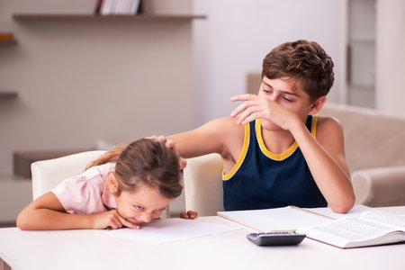 Schoolboy and his small sister staying at home during pandemicの写真素材