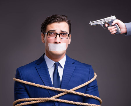 Businessman taken hostage and tied up with ropeの写真素材