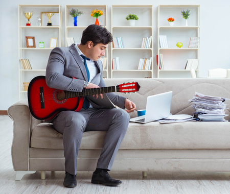 Businessman playing guitar at homeの写真素材