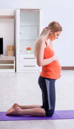 Pregnant woman doing sport exercise at homeの写真素材