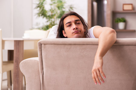 Young lazy man in oversleeping concept at homeの写真素材
