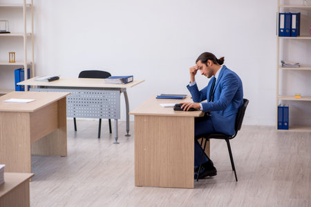 Young male employee and too much work in the officeの写真素材