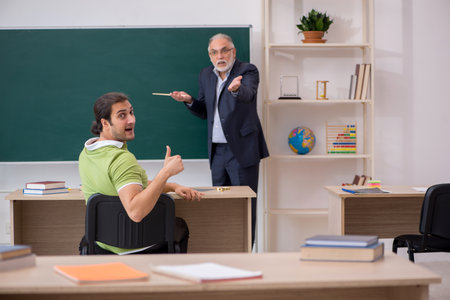 Aged teacher and male student in the classroomの写真素材