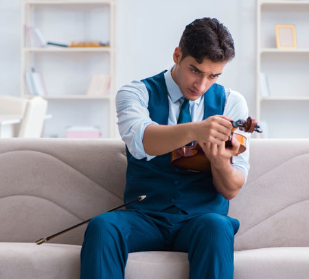 Young musician man practicing playing violin at homeの写真素材