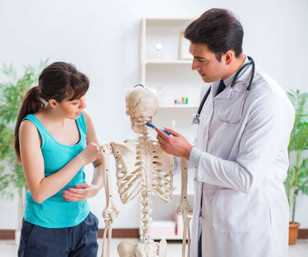Doctor showing type of injury on skeleton to patientの写真素材