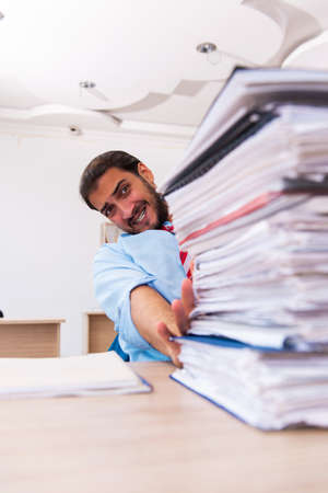 Young male employee unhappy with excessive work in the officeの写真素材