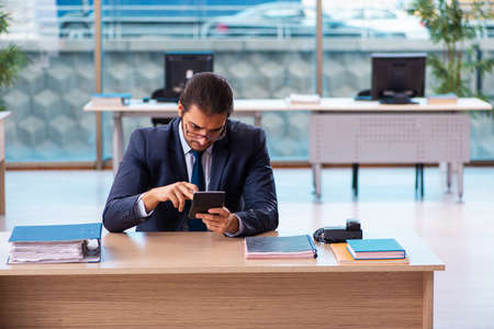 Young male bookkeeper working in the officeの写真素材