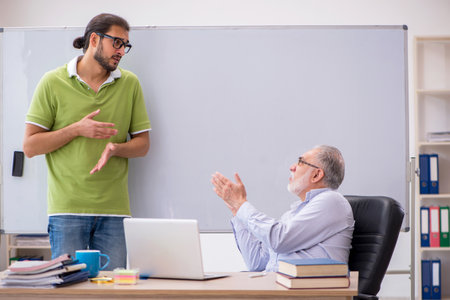 Old male teacher and young male student in the classroomの写真素材