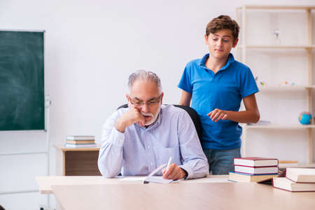 Old male teacher and schoolboy in the classroomの写真素材