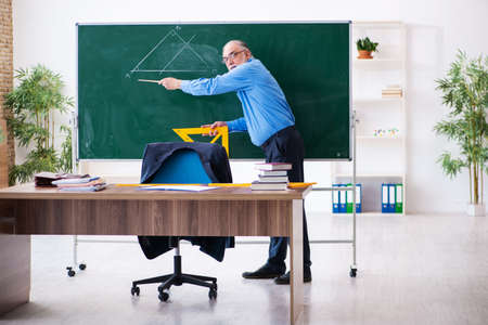 Old male geometry teacher holding triangleの写真素材