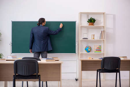 Young male teacher in front of green boardの写真素材