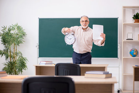 Old male teacher in time management conceptの写真素材