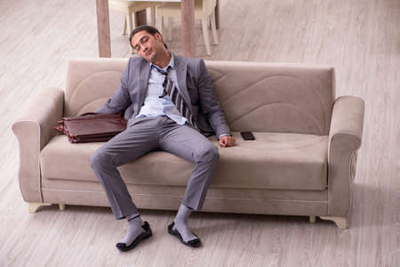 Tired young businessman coming home after working dayの写真素材