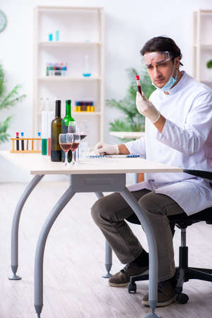 Male chemist examining wine samples at lab