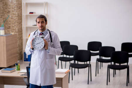 Young male doctor teacher in time management conceptの写真素材