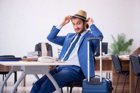 Young male employee preparing for trip in the officeの写真素材