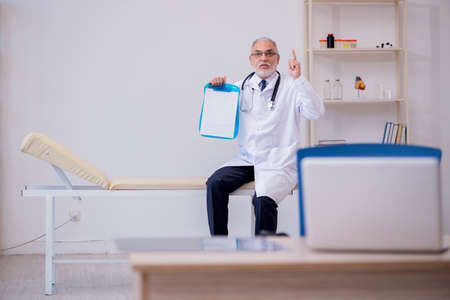 Old male doctor working in the clinicの写真素材