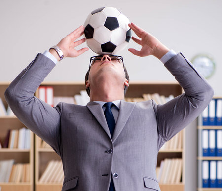 Businessman with football ball in officeの写真素材