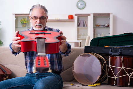 Senior male repairman repairing musical instruments at home