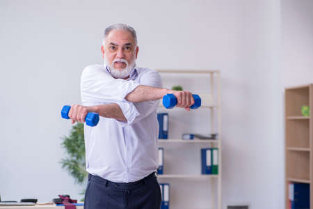 Aged male employee doing physical exercises during breakの写真素材