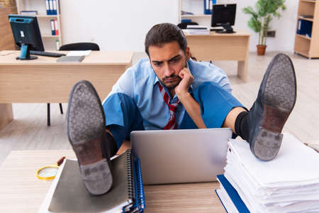 Young male employee unhappy with excessive work in the officeの写真素材