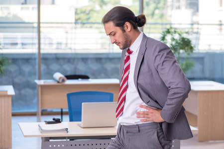 Young male employee doing sport exercises in the officeの写真素材