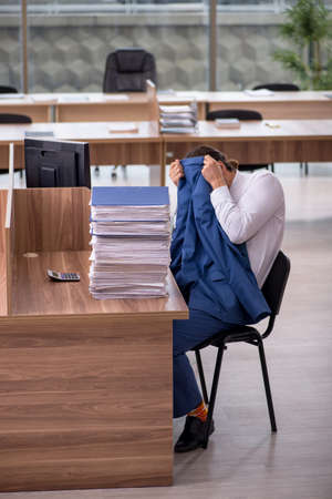 Young male employee unhappy with excessive work in the officeの写真素材