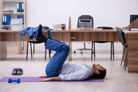 Young male employee doing sport exercises during break