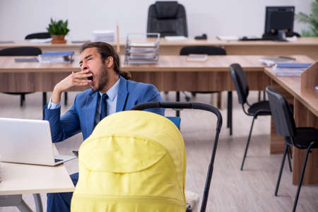 Young male employee looking after new born at workplaceの写真素材