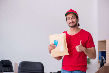 Young male courier delivering post to the office
