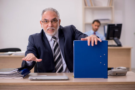 Old male boss and young employee working in the officeの写真素材