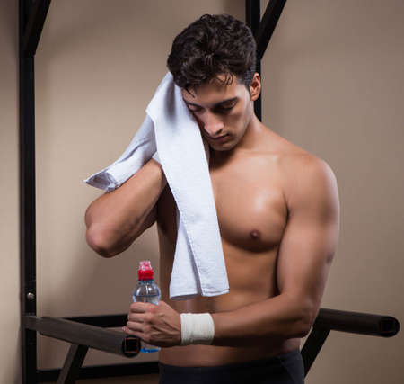 Thirsty man drinking water in sports gymの写真素材