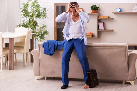 Young male employee getting up late at homeの写真素材