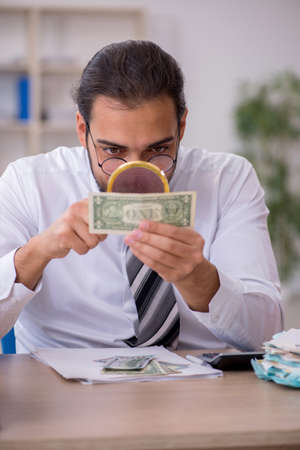 Young male bookkeeper in counterfeit bills conceptの写真素材