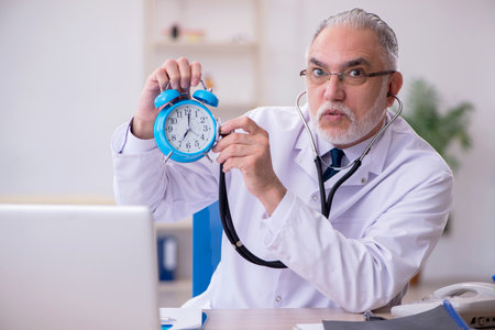Old male doctor in time management conceptの写真素材