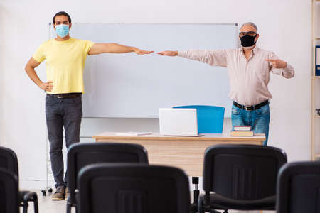 Young male student and experienced teacher in pandemic concept