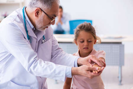 Small girl with her father visiting old male doctorの写真素材