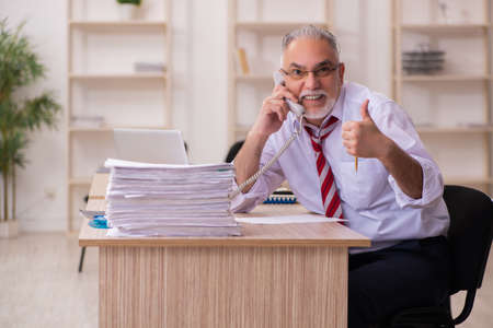 Old businessman employee sitting in the officeの写真素材