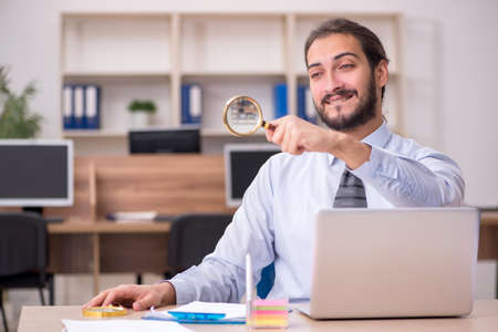 Young businessman employee holding loupe in auditing conceptの写真素材