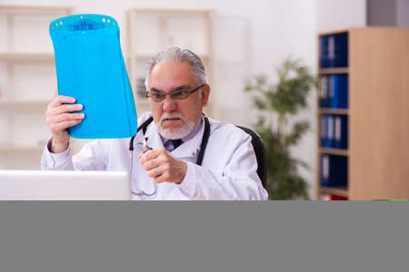 Experienced male doctor unhappy with excessive workの写真素材