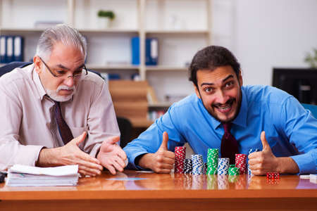 Two male employees playing cards at workplaceの写真素材