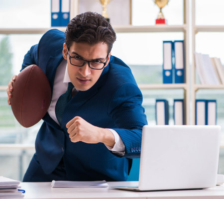 Businessman with american football in officeの写真素材