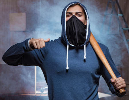 Hooligan with bat in dark room