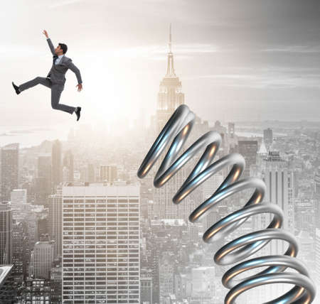 Businessman jumping from spring in promotion conceptの写真素材