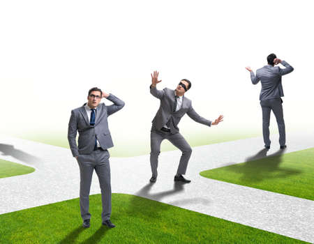 Young businessman at crossroads in uncertainty conceptの写真素材