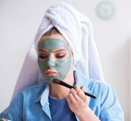 Woman applying clay mask with brush at homeの写真素材