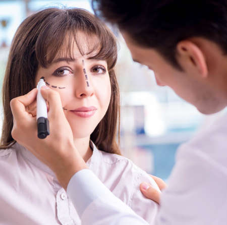 Plastic surgeon preparing for operation on woman faceの写真素材